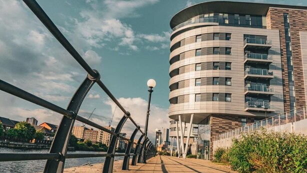 Un paseo marítimo con un edificio moderno que tiene balcones y un diseño curvo.