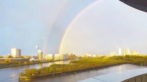Un paisaje urbano con un río, edificios y un arcoíris.