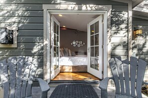 Ein Zimmer mit einem Bett, einem wandmontierten Spiegel und einer Tür zu einem anderen Raum.