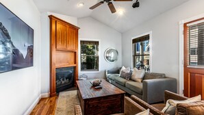 Un salon avec une cheminée, un ventilateur de plafond, un canapé et une table basse.