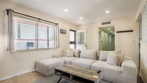 A living room with a sectional sofa, a coffee table, and a large window with blinds. - Comfortable Eastside El Paso Home for Families, Nurses & Work Stays (El Paso)