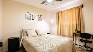 A bedroom with a bed, a nightstand, a desk with a chair, and a ceiling fan. - Comfortable Eastside El Paso Home for Families, Nurses & Work Stays (El Paso)