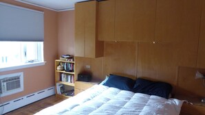 Ein Schlafzimmer mit einem Bett, einem Bücherregal und einem Fenster.