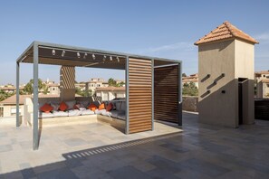 Eine Dachterrasse mit überdachter Sitzgruppe, einem kleinen turmartigen Aufbau und Blick auf die umliegenden Gebäude.