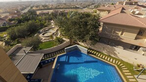 A residential area with a swimming pool, a view of the city, and a large tree. - ALSAWAH Majestic 6BR Residence & Oasis (6th of October City)