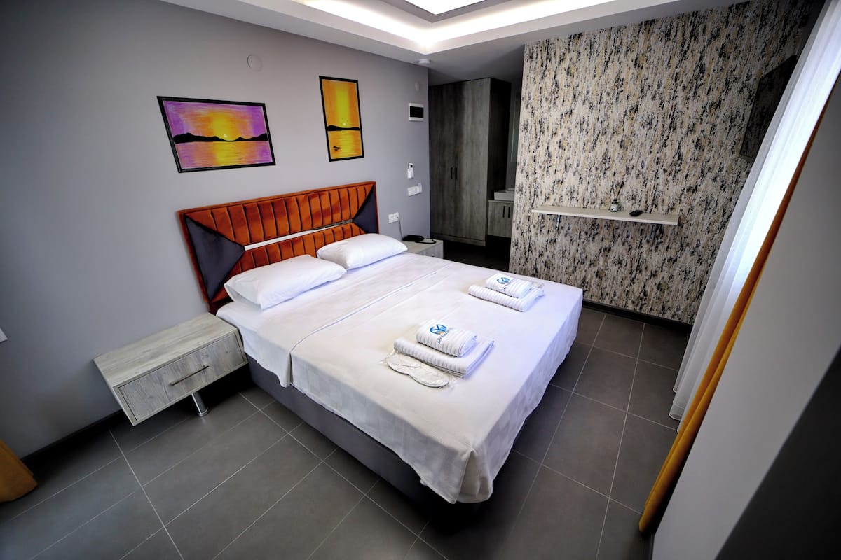 Ein Hotelzimmer mit Bett, Nachttisch, Kleiderschrank und einem durchgegangenen Tür sichtbaren Badezimmer.