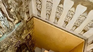 Una escalera con barandilla de madera y un mural en la pared.