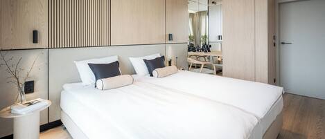 Un dormitorio moderno con una cama grande, una mesita de noche, un espejo y un armario.