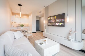 A modern living room with a sofa, coffee table, and a TV mounted on the wall displaying various channels.