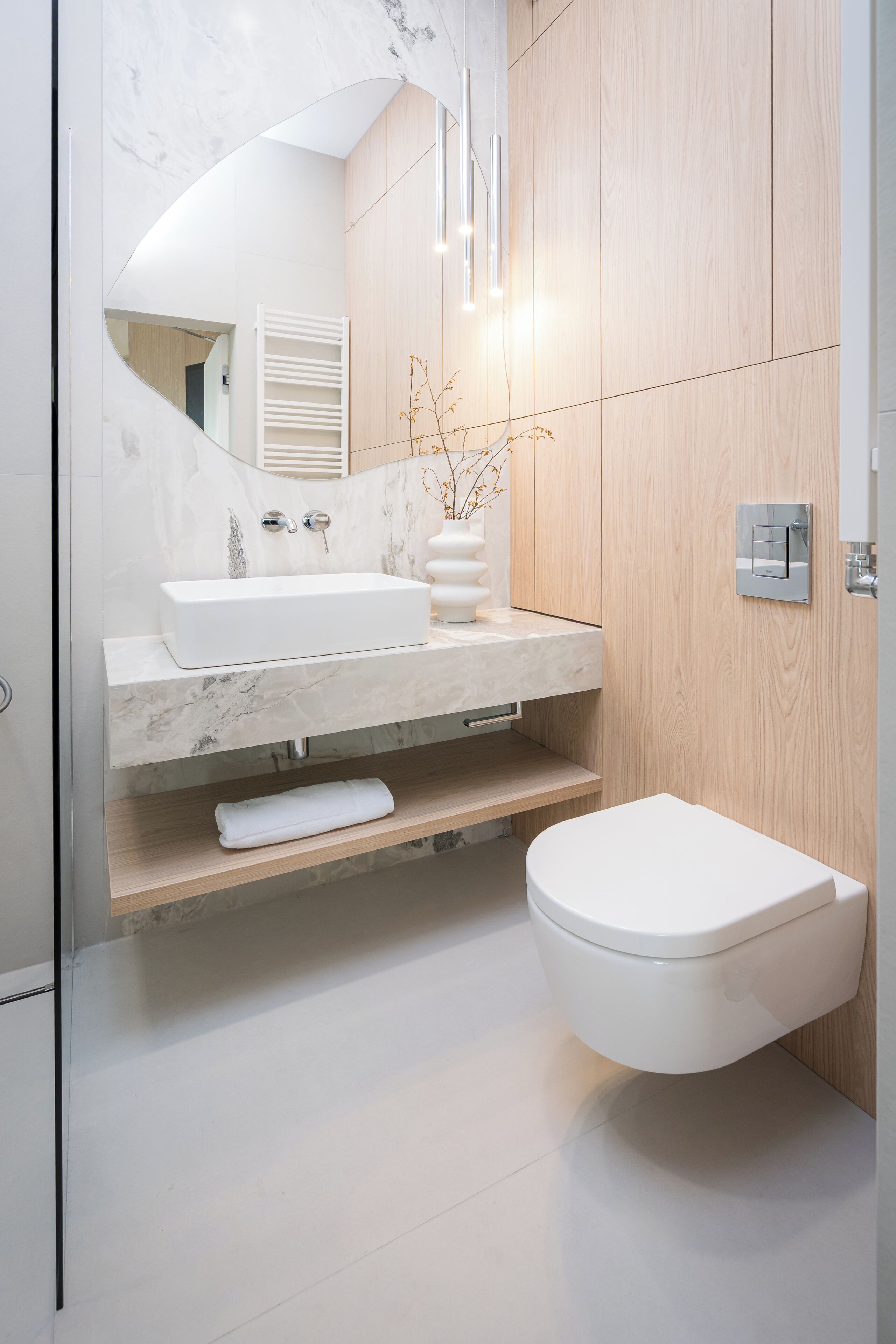 A modern bathroom with a white sink, mirror, and toilet.