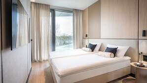 A modern hotel room with a large bed, a bedside table, a mirror, and a view of the outdoors. - Apartamenty Kapitańska by Elite4Rent (Olsztyn)