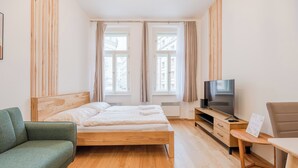 Un dormitorio con cama, televisor, sofá y escritorio.