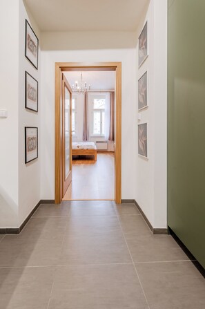A hallway leading to a bedroom with a bed, framed pictures on the walls, and a wooden door. - Perfect 1-bedroom apartment in the heart of Hlavní město Praha (Hlavní město Praha)