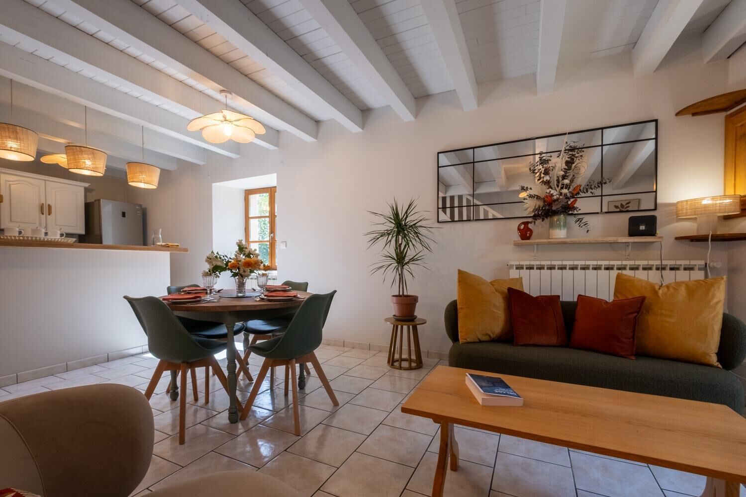 A modern living room with a dining area, a sofa, a coffee table, and a potted plant.
