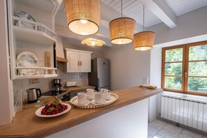 Eine moderne Küche mit weißen Schränken, einer Holz Arbeitsplatte und drei hängenden Korblampen.
