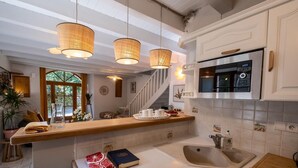 Una cocina con encimera de madera, microondas integrado y un lavamanos.
