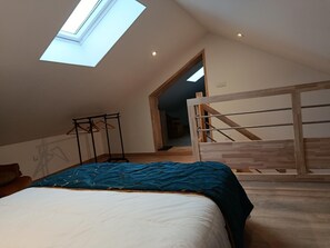 Ein Schlafzimmer mit Oberlicht, einem Bett, einer Holztreppe und einem Flur.