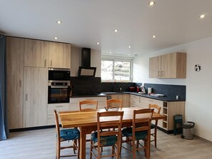 Une cuisine moderne avec des meubles en bois, une table à manger avec des chaises et une fenêtre qui laisse entrer la lumière naturelle.