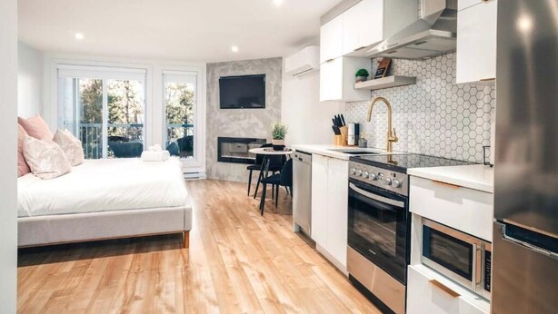 A modern kitchen with a dining area, a built-in oven, a microwave, and a large window. - LAO LOFT 106 by Gestion ELITE (Mont-Tremblant)