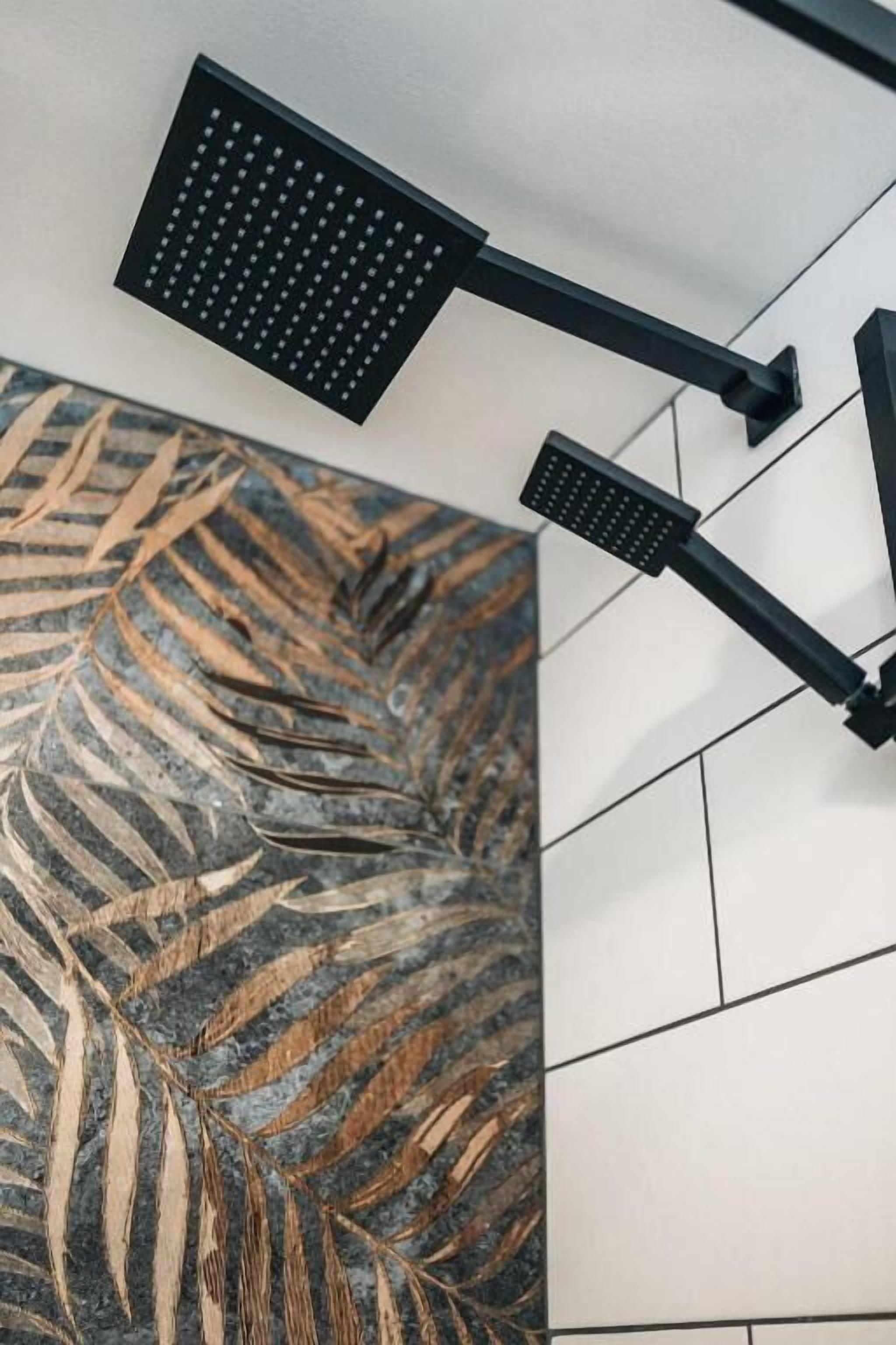 Une salle de bain dotée d’une douche au design moderne, d’un mur décoratif recouvert de carreaux et d’un plafond apparent.