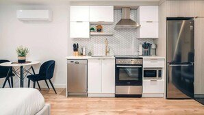 A modern kitchen with white cabinets, a stainless steel refrigerator, an oven, and a dishwasher. - LAO LOFT 106 by Gestion ELITE (Mont-Tremblant)