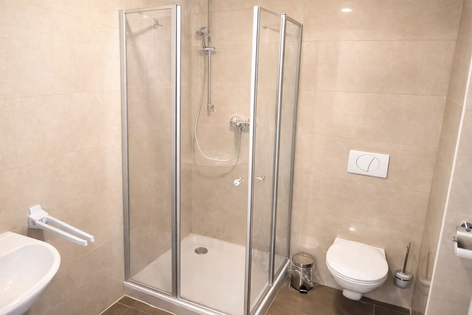 Un baño con ducha de vidrio, inodoro y lavamanos.