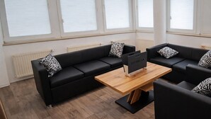 A modern living room with black sofas, a wooden coffee table, and zebra-patterned pillows. - Check-Inn Hotel - Offenbach (Offenbach am Main)