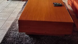 Un saló amb un sofà modular, una taula de centre de fusta i una cuina al fons.