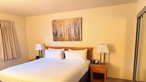 Ein Hotelzimmer mit einem großen Bett, zwei Nachttischen mit Lampen, einem Bild an der Wand und einer Schiebetür.