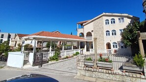 A multi-story building with a covered entrance, stone steps, and a gated driveway.