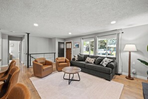 A modern living room with a sofa, two armchairs, a coffee table, and a lamp. - Spacious 4-bedroom House close to Lake Coeur d'Alene and Downtown (Coeur d'Alene)