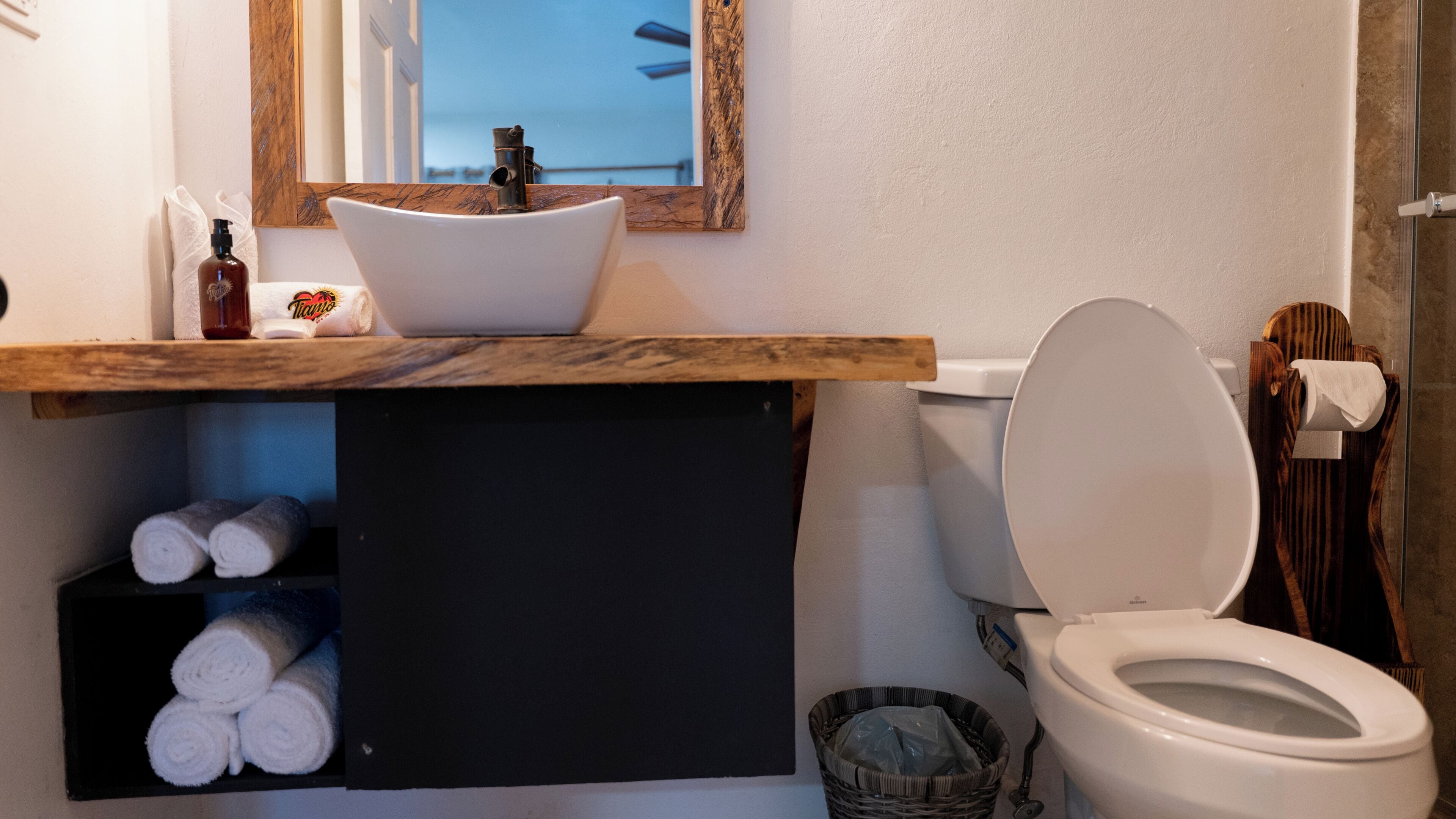 A bathroom with a white sink, a toilet, and a shelf with towels.