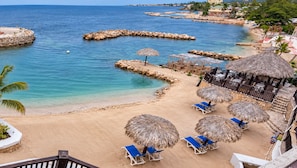 A beach with clear blue water, a sandy shore, and thatched umbrellas. - Tiamo Beach Resort and Spa (Runaway Bay)