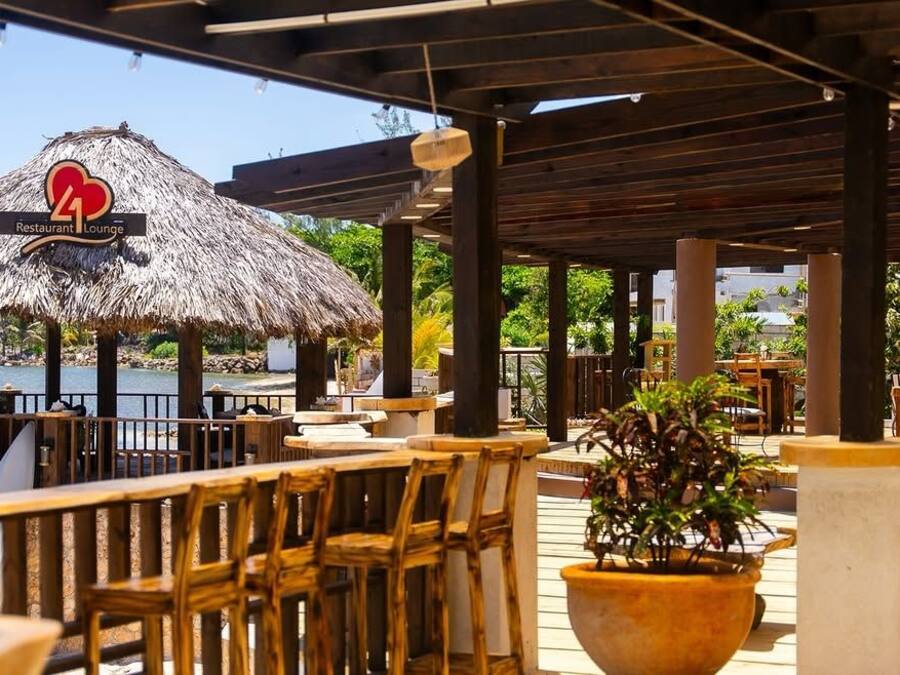 An outdoor restaurant with wooden furniture and a thatched roof structure.
