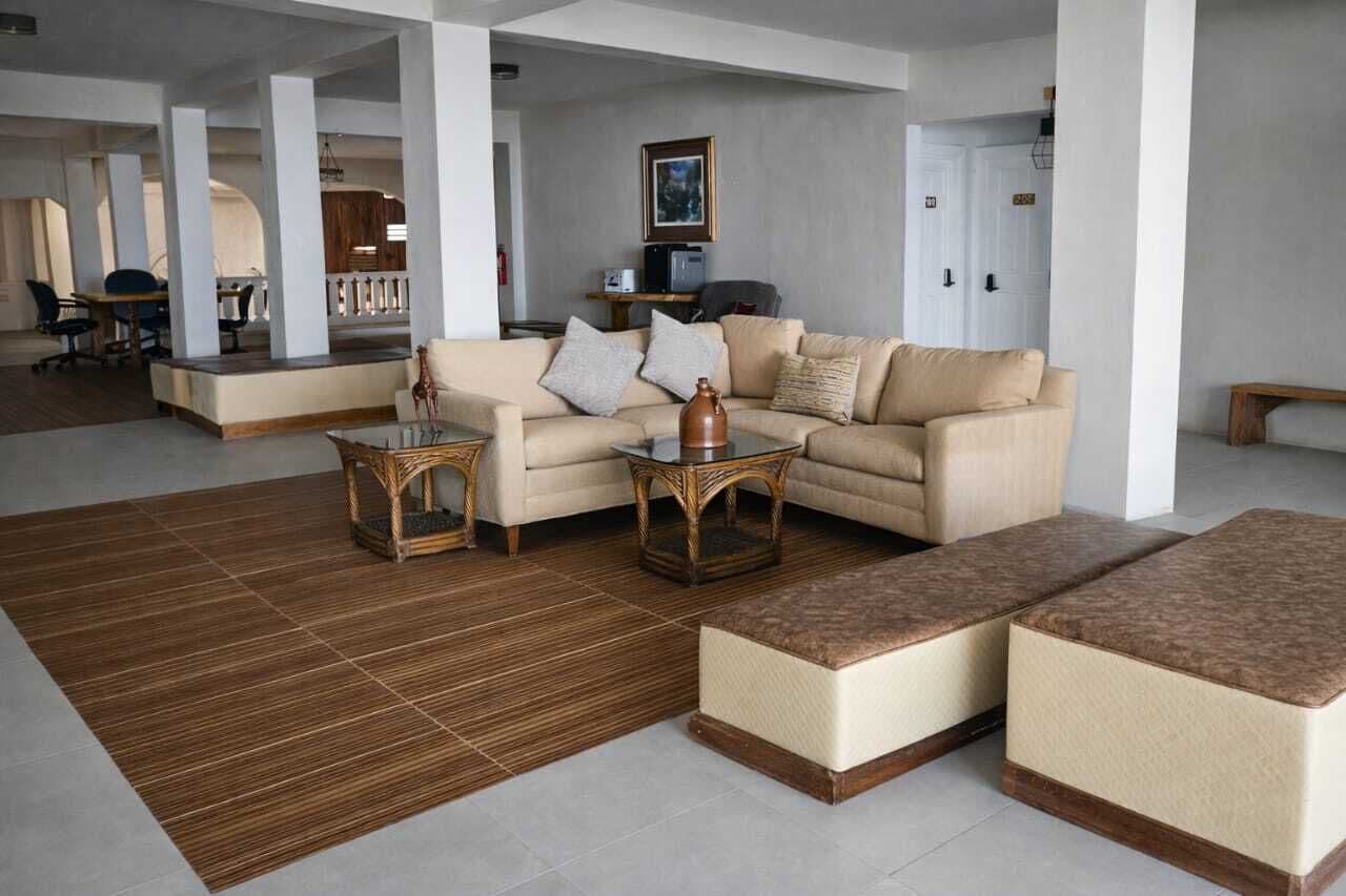 A spacious living area with a sofa, coffee table, and ottomans, a dining area with chairs and a table, and a kitchen area with appliances.