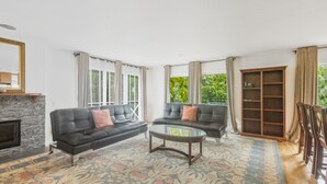 A living room with a fireplace, two black sofas, a glass coffee table, and a patterned rug. - 2 for 1 Stay: Jacuzzi/Starlit Mtn Skies/Near Beach (Waimea)
