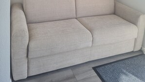 Un sofá color beige en una habitación con un cuadro de un paisaje urbano en la pared.