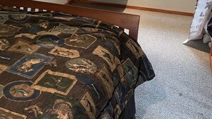 Ein Schlafzimmer mit einem Bett, einem Fernseher auf einem Regal, einem Fenster mit Jalousien und einem Willkommensschild.