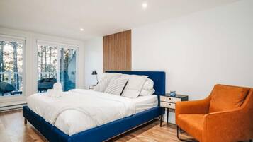 Une chambre à coucher comprenant un lit, une table de chevet, une chaise et une fenêtre donnant sur des arbres.