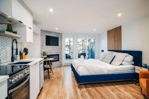 Un dormitorio moderno con una cama azul, una pequeña cocina y vistas al exterior.