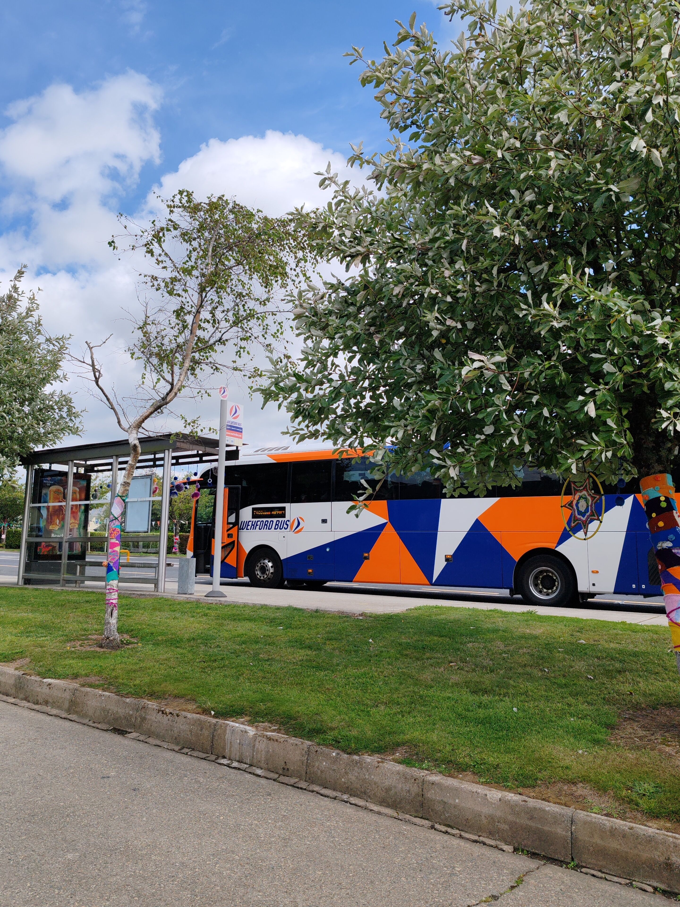 Un arrêt de bus avec un abri, un autobus et un arbre.