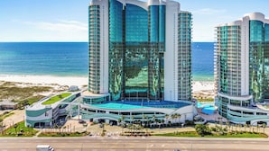 Ein modernes Hotel mit einer geschwungenen Fassade, mehreren Balkonen und einem Poolbereich.