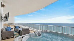 Ein Balkon mit Whirlpool, Korbmöbeln, einem Flachbildfernseher und Blick auf den Ozean.