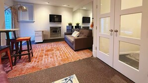 En moderne stue med sofa, fjernsyn, et køkken og et spisebord med stole.