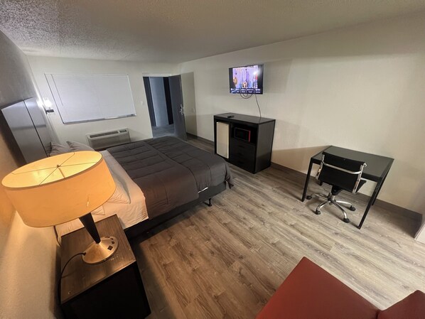 A bedroom with a bed, a desk, a TV, and a lamp. - Skylite inn (Austin)