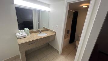 A bathroom with a sink, mirror, and a shower area.