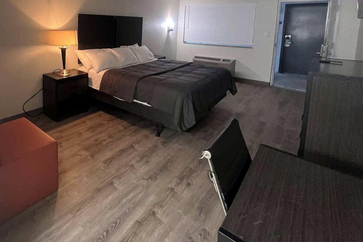 Een slaapkamer met een bed, bedlamp en een raam met jaloezieën.