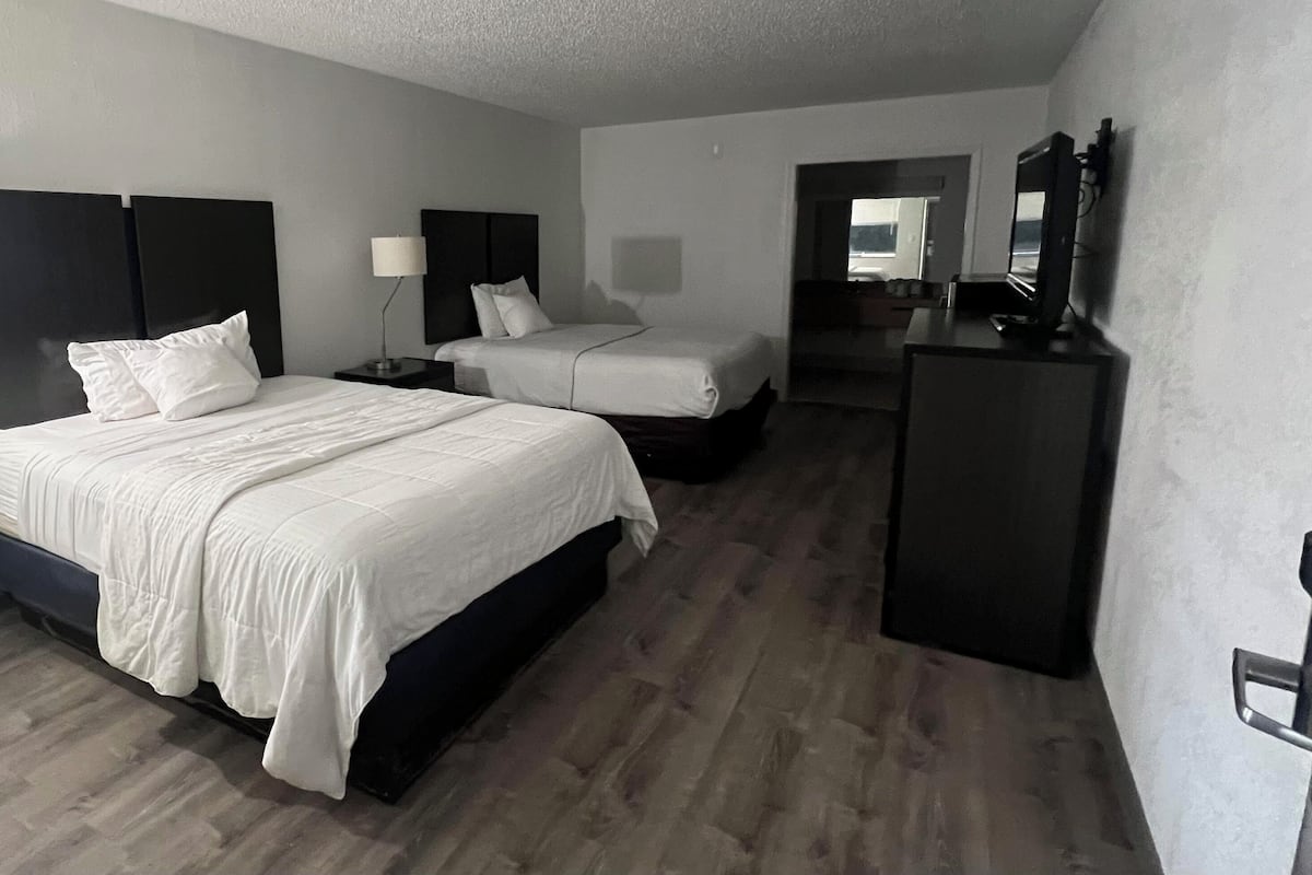 Een hotelkamer met een groot bed, een kleiner bed, een bureau, een spiegel en een kledingkast.
