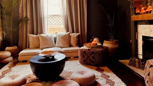 Ein gemütliches Wohnzimmer mit einer Couch, Hocker, einem Couchtisch und einem Kamin.