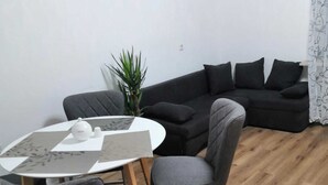 Uma sala de estar moderna com uma mesa redonda, sofá cinzento e um vaso de planta.